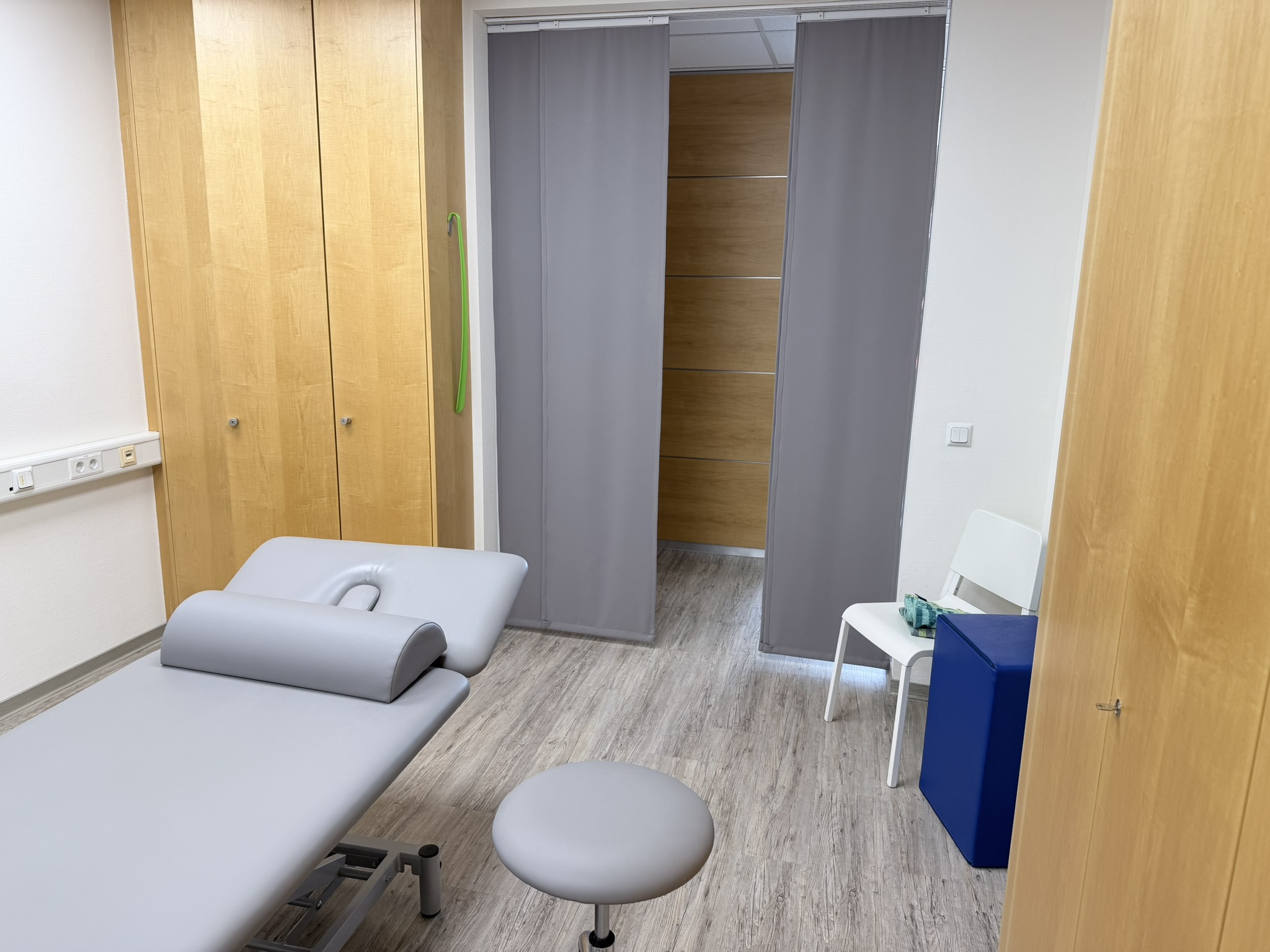 Heller Behandlungsraum mit Liege und Hocker